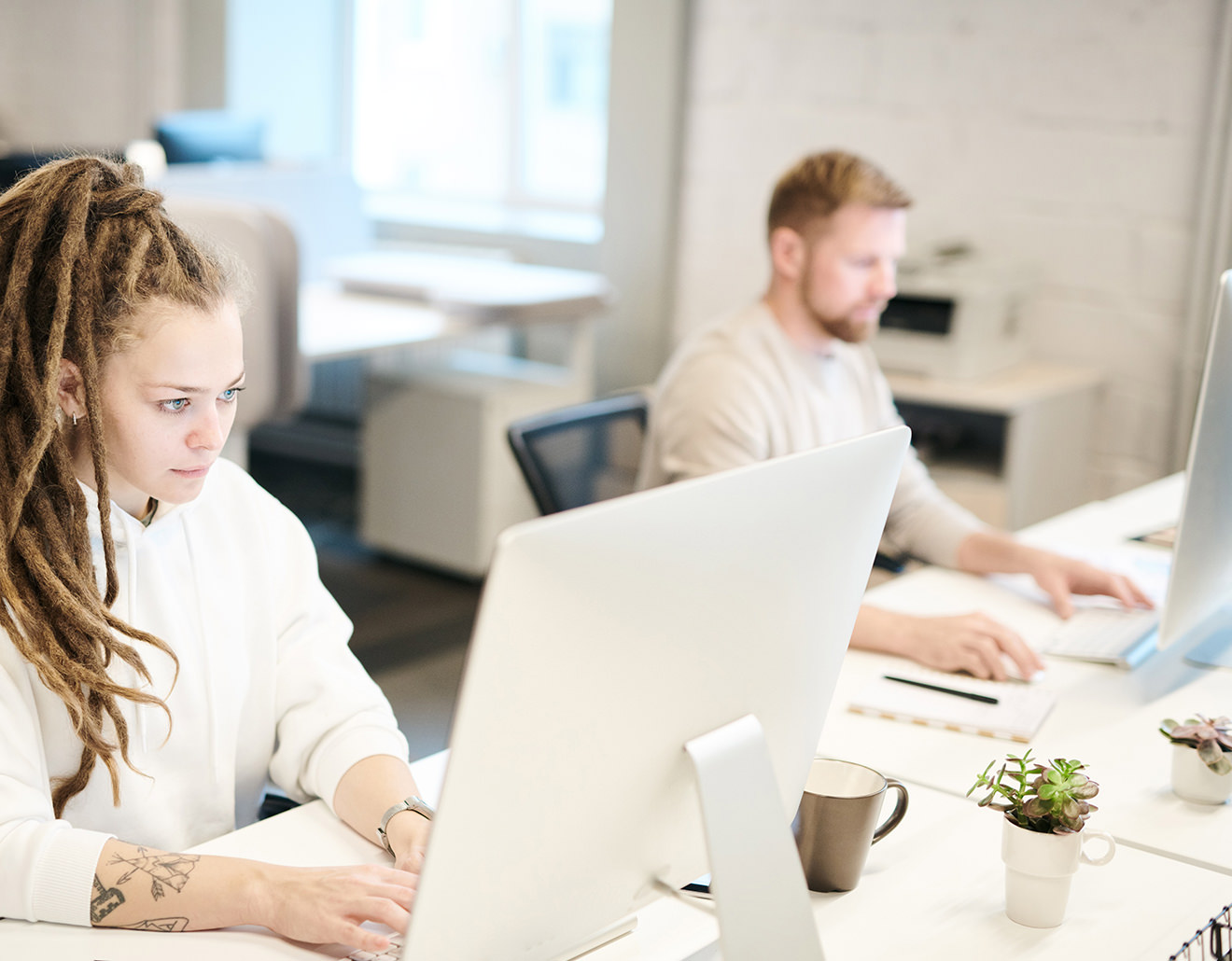 A man and woman working on computers in the office