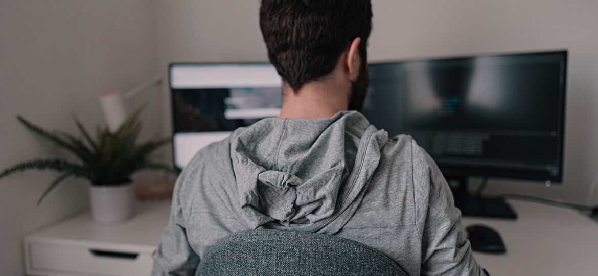 A male with a grey hooded long sleeve sitting at his desk using JetStream DataFile Transfer services
